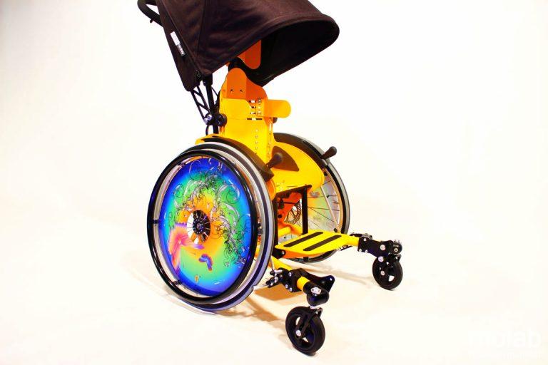 Seitenansicht des molab Chillie Rollstuhls in Gelb mit Regenverdeck.