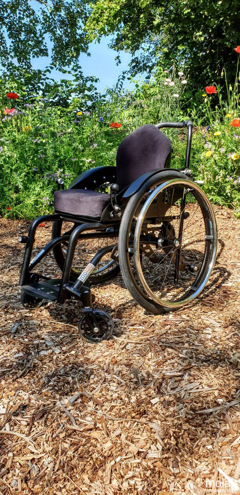 Molab G6KID Rollstuhl im Garten auf Rindenmulch.