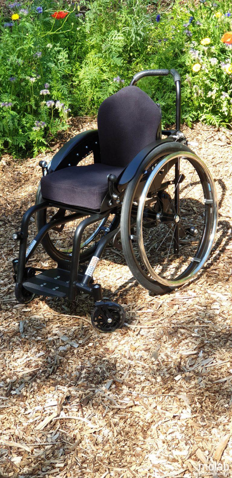 Molab G6KID Rollstuhl im Garten auf Rindenmulch.