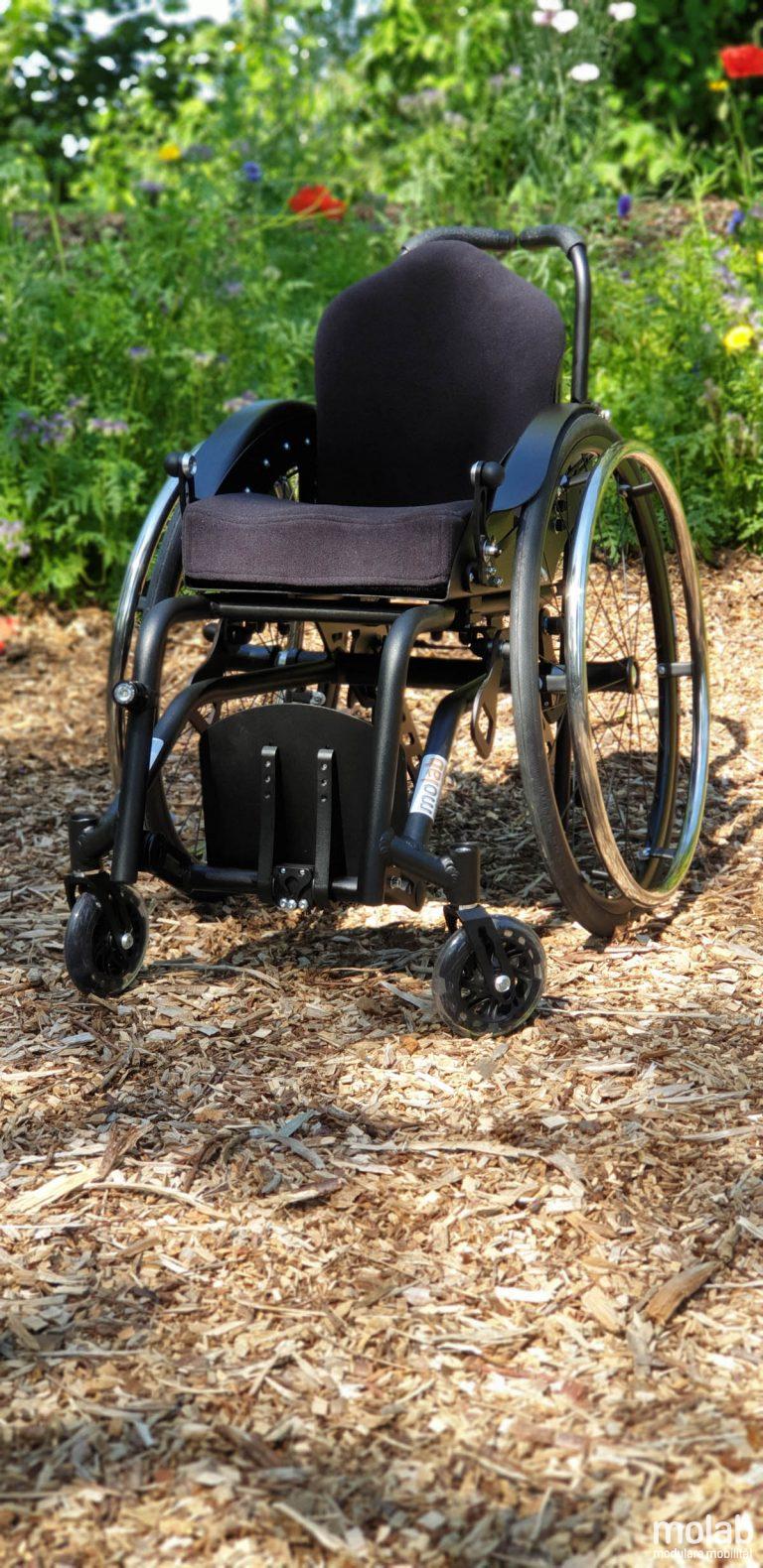 Molab G6KID Rollstuhl im Garten auf Rindenmulch.
