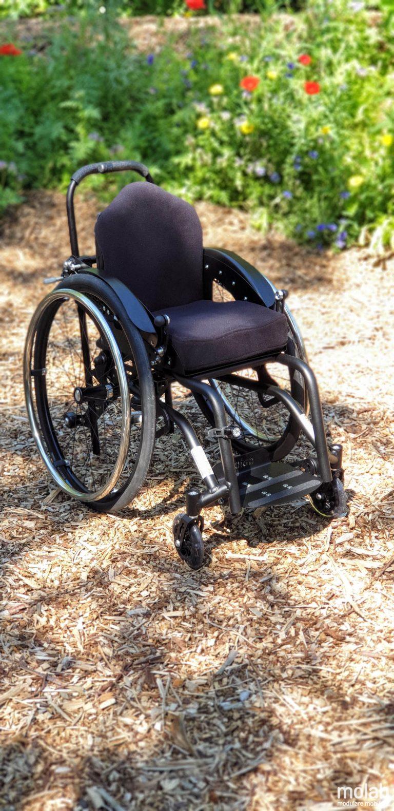 Molab G6KID Rollstuhl im Garten auf Rindenmulch.