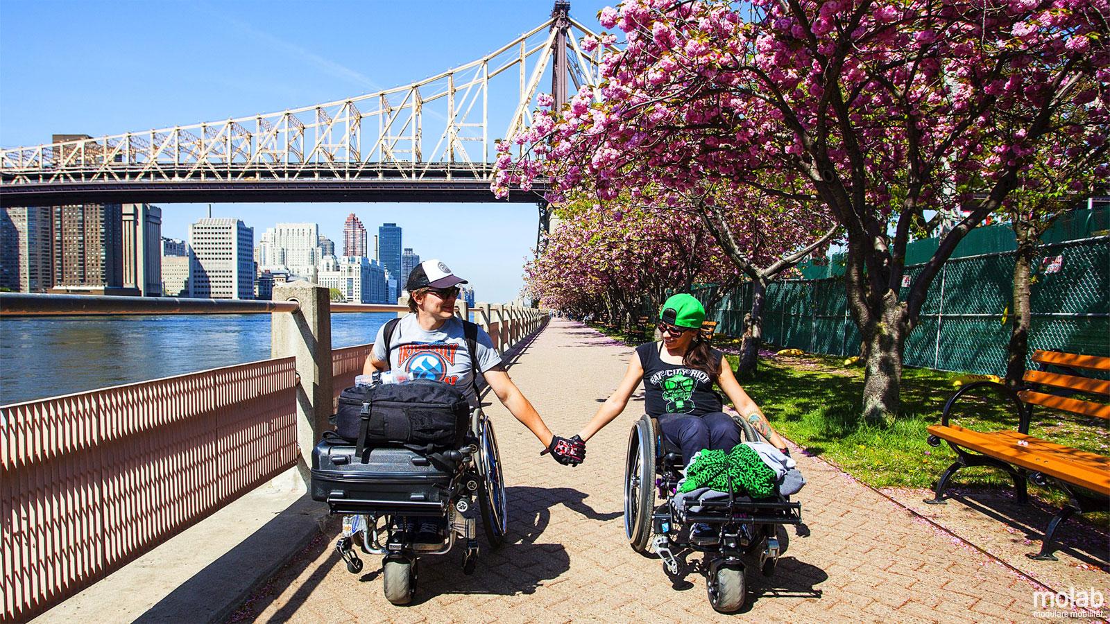 Zwei Rollstuhlfahrerinnen auf einem Weg an einem Fluß mit jeweils einem Smartwheel von Molab